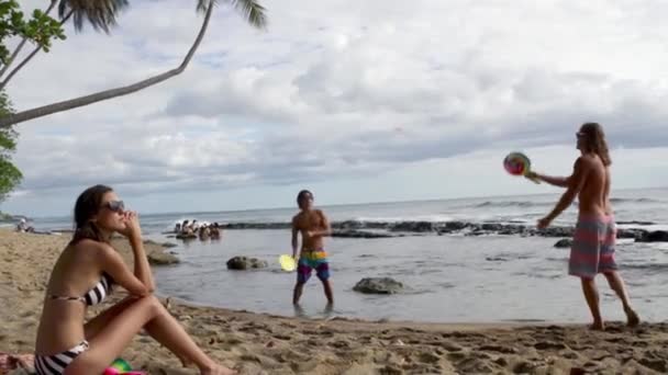 Lidé na pláži, muži hrají pálku a míčové hry