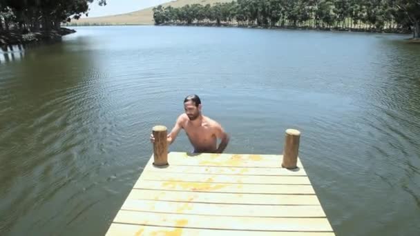 男子在码头上从湖中爬出来 对着镜头微笑 — 图库视频影像