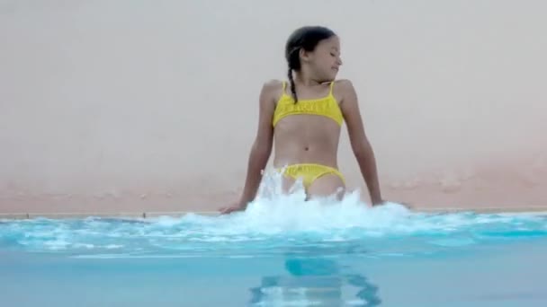 女孩坐在池边和踢和飞溅的水 — 图库视频影像