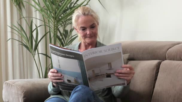 Reife Frau Liest Magazin Auf Dem Sofa — Stockvideo