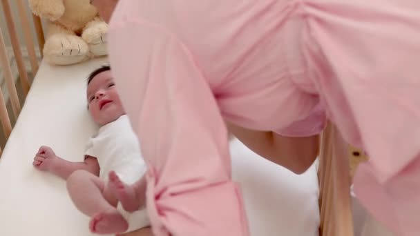 自宅でベビーベッドに赤ちゃんを置く母親 — ストック動画