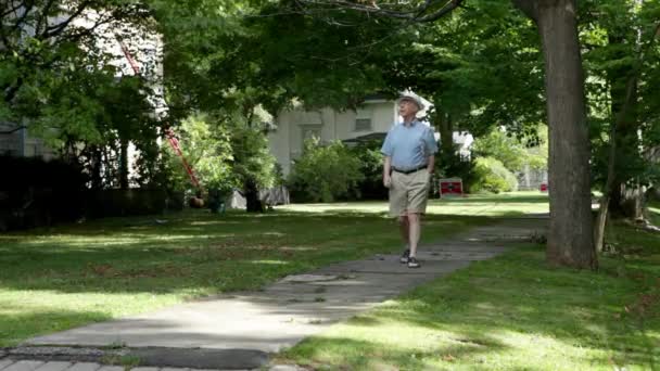 近所を歩いて新聞で年配の男性 — ストック動画