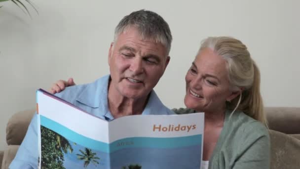 Ouder Paar Kijken Naar Vakantie Brochure — Stockvideo