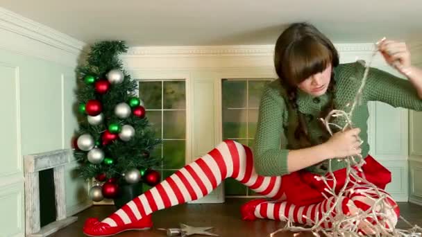 イライラし 小さな部屋でクリスマス ツリーを飾るためにしようとしている若い女性 — ストック動画