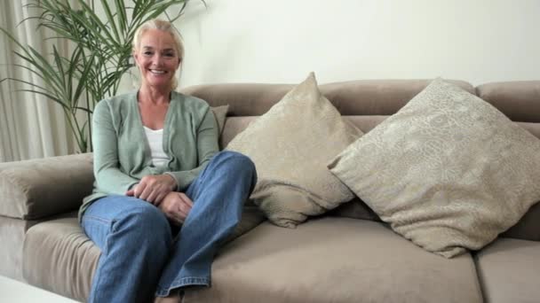 成熟した女性のリビング ルームのソファでリラックス — ストック動画