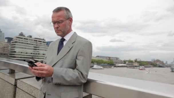 Biznesmen Przy Użyciu Smartfona Przez Rzeki Mieście — Wideo stockowe
