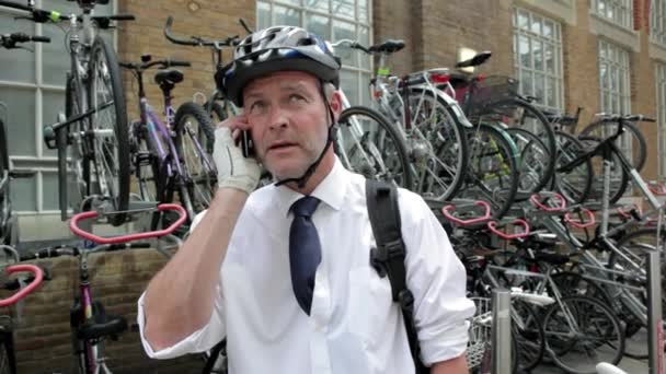在手机上谈论自行车头盔的商人 — 图库视频影像