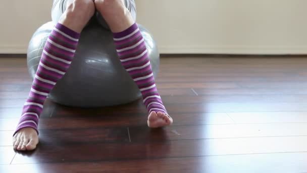 在普拉提球的条纹腿加热器的妇女 — 图库视频影像