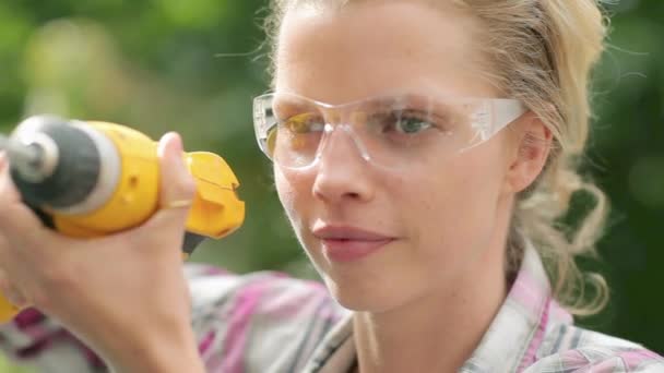 带电钻的安全护目镜的妇女 — 图库视频影像