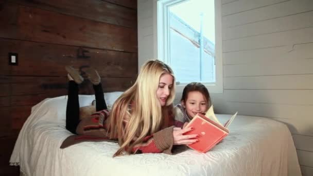 母亲和女儿躺在床上看书 — 图库视频影像