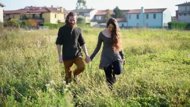 年轻夫妇牵手走在草地上 — 图库视频影像