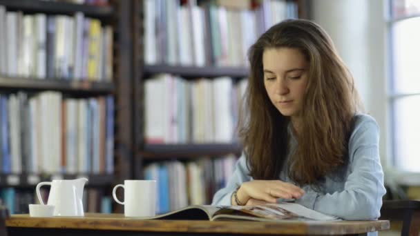 Νεαρό Κορίτσι Περιοδικό Ανάγνωσης Στη Βιβλιοθήκη — Αρχείο Βίντεο