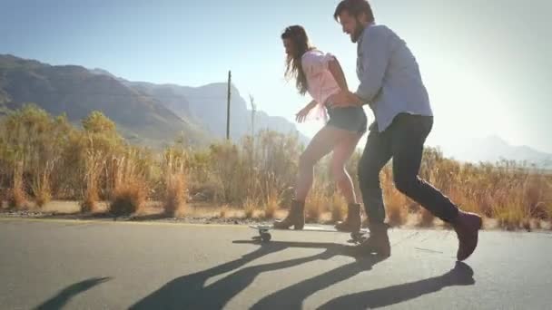 男子在滑板上推女人的侧视图 — 图库视频影像
