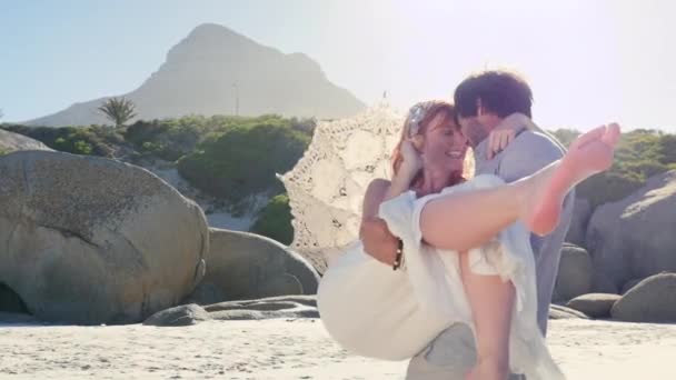 Man Draagt Vrouw Met Parasol Het Strand — Stockvideo