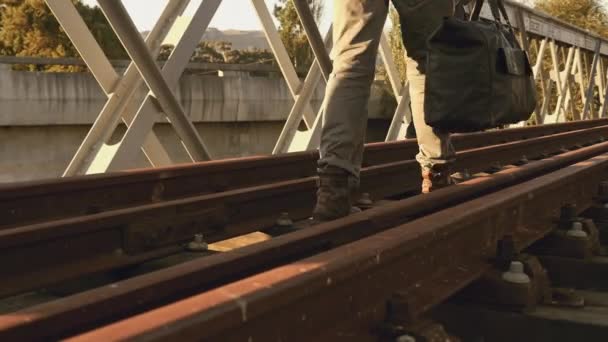 荷物を持った3人の男が鉄道線路を歩いている — ストック動画