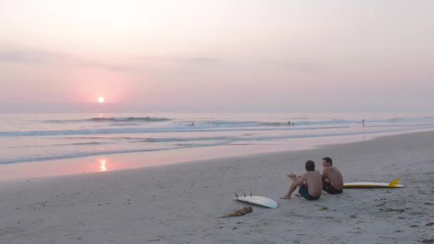 Deux Jeunes Hommes Assis Sur Plage Coucher Soleil — Video