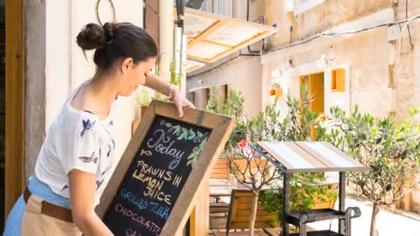 Mujer Colocando Menú Pizarra Por Restaurante — Vídeos de Stock