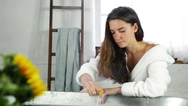 Νεαρή Γυναίκα Στο Λευκό Μπουρνούζι Στύψιμο Σφουγγαριού — Αρχείο Βίντεο