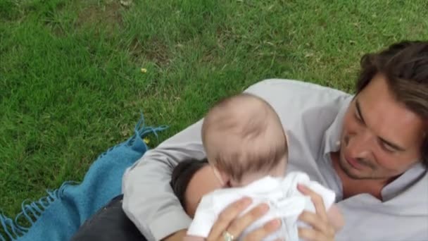 Paar Liegt Auf Gras Und Spielt Mit Baby — Stockvideo