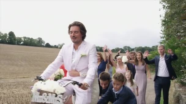 Invités Suivant Jeunes Mariés Faisant Vélo Dans Paysage Rural Dinton — Video