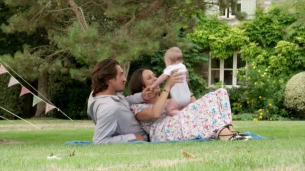 夫妇躺在花园里和玩男婴 — 图库视频影像