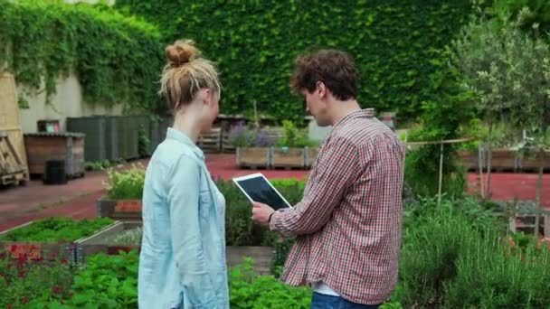 都会の庭でデジタルタブレットを使用して若いカップル — ストック動画