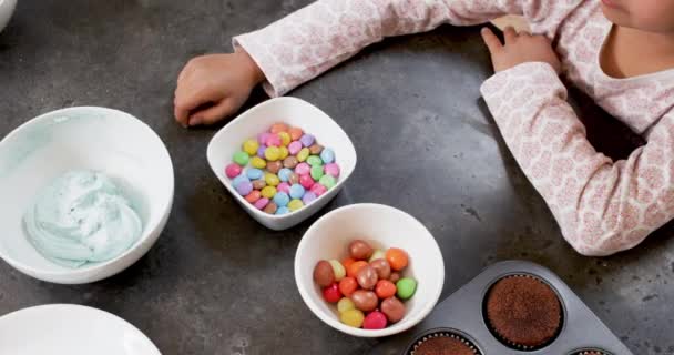 女の子と男の子は台所でボウルからキャンディーを食べる — ストック動画