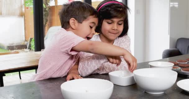 女孩和男孩在厨房里用碗吃糖果 — 图库视频影像