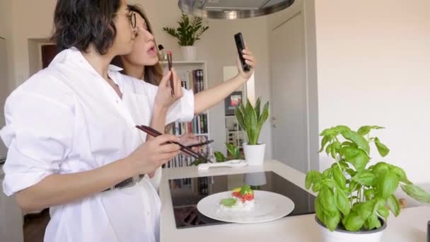 Dos Mujeres Comiendo Con Palillos Sushi Haciendo Una Videollamada Cocina — Vídeo de stock