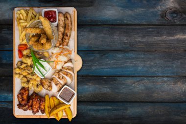 Bira aperatifler küme. Tavuk parçaları kesme tahtası ahşap arka plan ile servis. Üstten görünüm.