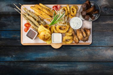 Bira aperatifler küme. Balık küme kesme tahtası ahşap arka plan üzerinde Kupalar ile servis.