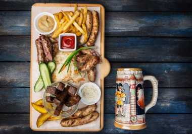 Bira aperatifler küme. Izgara sosis ve domates ve barbekü sosu, antika kupa ile kesme tahtası üzerinde hizmet ile patates kızartması.