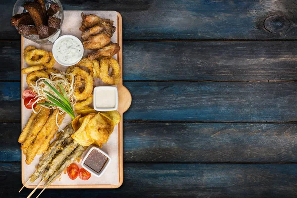 Conjunto de aperitivos de cerveza. Set de pescado servido en tabla de cortar con las tazas, sobre el fondo de madera . — Foto de Stock