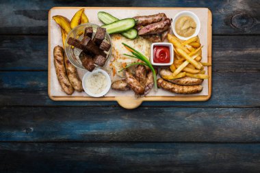 Bira aperatifler küme. Izgara sosis ve domates ve kesme tahtası üzerinde hizmet Barbekü sosu, patates kızartması.