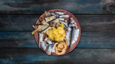 Aperatifler bira için. Tuzlanmış, kurutulmuş balık, kalamar halkaları ve patates cipsi, kesme tahtası üzerinde döndürme