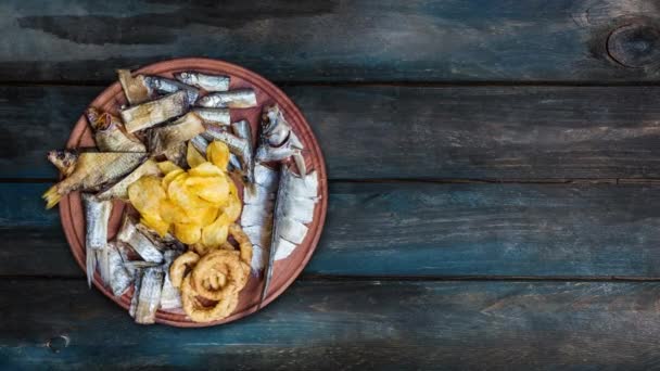 Snacks für Bier. gesalzener, getrockneter Fisch, Tintenfischringe und Kartoffelchips rotieren auf dem Schneidebrett. mit dem Kopierraum für Ihren Text. — Stockvideo