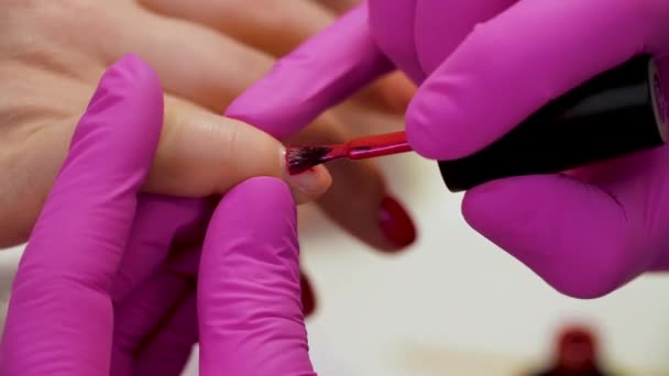 Specialisten täcker klientens nagel med röd lack. Närbild — Stockvideo