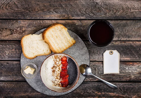 Pequeno-almoço saudável. Cereais de arroz ou mingau de cereal com morango fresco, amêndoa e flocos de coco, servido com pão, manteiga e suco de baga. Em um belo fundo de madeira, vista superior — Fotografia de Stock