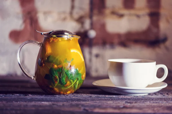 Чай з обліпихою з м'ятою та фруктами на дерев'яному столі. Подається чашка і блюдце — стокове фото