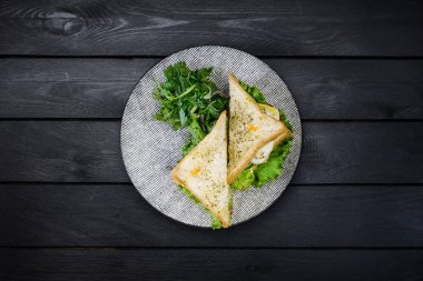 Tavuk ve sebze seramik plaka ile sandviç. Siyah ahşap arka plan üzerinde görünümü top