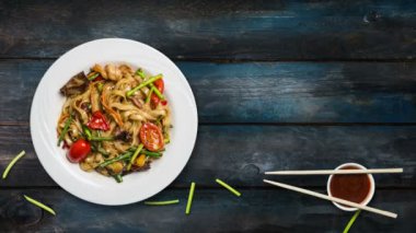 Udon stir fry erişte deniz ürünleri ve sebze ile döner. Taze fasulye filizi ve chopsticks ahşap arka plan üzerinde beyaz bir plaka ile dekore edilmiştir. Metniniz için kopya alanı ile Üstten Görünüm