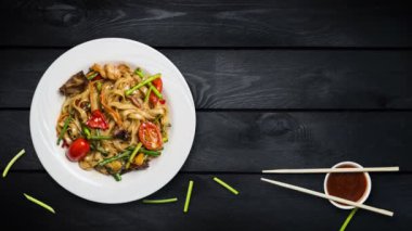 Udon stir fry erişte deniz ürünleri ve sebze ile döner. Taze fasulye filizi ve chopsticks siyah ahşap zemin üzerine beyaz bir plaka ile dekore edilmiştir. Metniniz için kopya alanı ile Üstten Görünüm