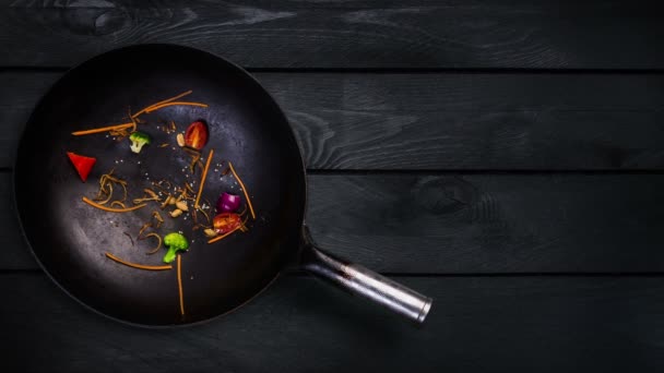 Animation. Ingredients for noodle wok in a frying pan for frying on a black wooden background — Stock Video