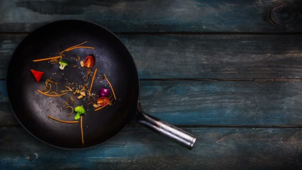 Animação. Ingredientes para macarrão wok em uma frigideira para fritar em um fundo de madeira — Vídeo de Stock