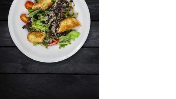 Salade avec saumon en chapelure avec laitue et graines de sésame. Rotation sur fond en bois noir. Mise en page carrée pour les réseaux sociaux et espace de copie pour votre texte . — Video