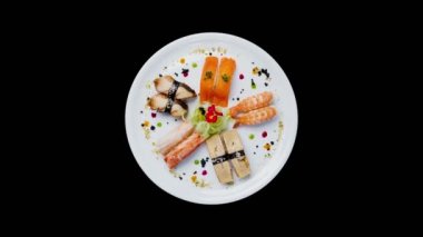 Sashimi küçük çiçekler, Japon yemekleri ile dekore edilmiş bir beyaz yuvarlak plaka üzerinde dönen ayarlayın. Üstten Görünüm. Siyah bir arka plan üzerinde izole