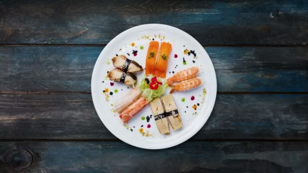 Вращающиеся сашими установлены на белой круглой тарелке, украшенной маленькими цветами, японской едой, видом сверху. Увлажненный фон с пространством для копирования текста — стоковое видео