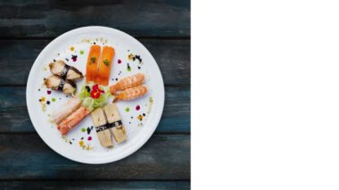 Japon yemekleri. Beyaz yuvarlak tabağa ayarla sashimi dönen, küçük çiçekler, üstten görünüm ile dekore edilmiş. Ahşap arka plan, sosyal ağlar için kare düzen kopya alanı metni