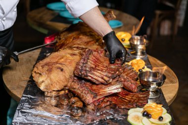 Bir gümüş tepsi üzerinde tuğla fırında pişmiş kuzu ve kuzu kaburga yakıcı kase ve meyve ile dekore edilmiş.