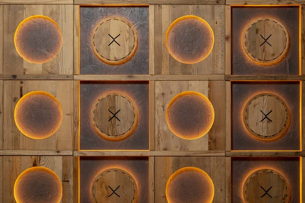 Decorative wall handmade with orange lighting made of wood in the form of squares and circles in them.